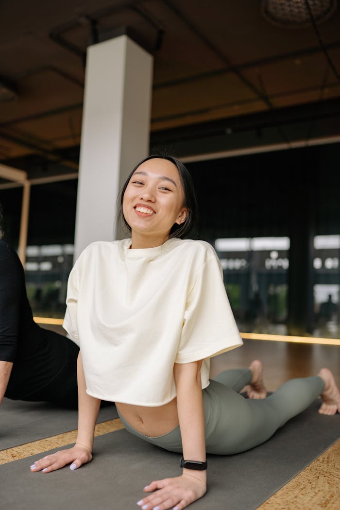 Cheerful woman performing a yoga pose on a mat in an indoor studio, embracing fitness and wellness.